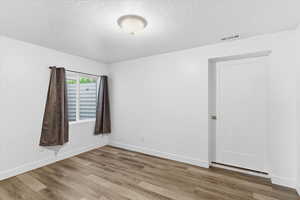 Unfurnished room featuring wood finished floors and a textured ceiling