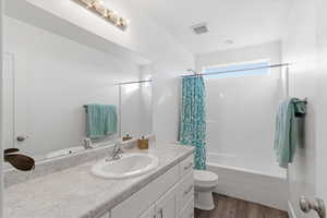 Bathroom with vanity, shower / tub combo, and light wood finished floors