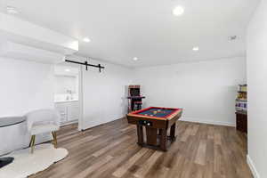 Game room featuring a barn door, wood finished floors, and recessed lighting