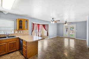 Kitchen featuring a peninsula, glass insert cabinets, wood finish cabinets, light countertops, and open floor plan