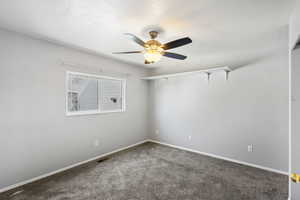 Empty room featuring dark colored carpet and a ceiling fan
