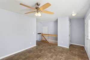 Empty room featuring stone finish floors and ceiling fan