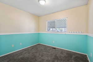 Empty room featuring dark colored carpet and baseboards