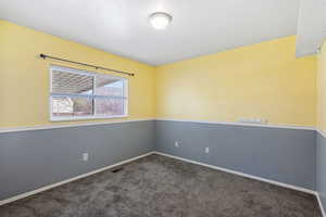 Empty room featuring dark carpet and baseboards