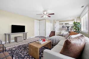 Living room featuring ceiling fan and dark carpet