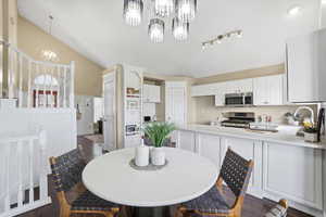 Dining room with dark wood-type flooring, hanging lights, and vaulted ceiling