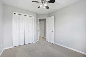 Unfurnished bedroom with ceiling fan, carpet, and a closet