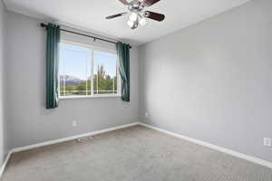 Empty room with a ceiling fan, carpet floors, and a mountain view