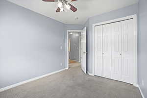 Unfurnished bedroom featuring carpet floors, ceiling fan, and a closet
