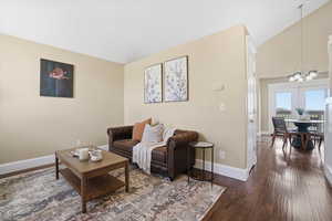Living area with lofted ceiling, hanging lights, and dark wood finished floors