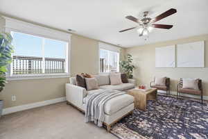 Carpeted living room featuring ceiling fan and baseboards