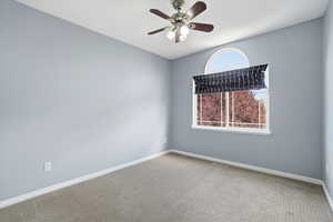 Empty room with a ceiling fan and carpet flooring