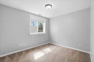 Spare room featuring light carpet and baseboards