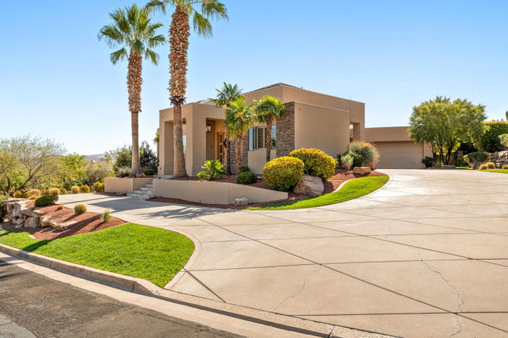 Southwest-style home with stucco siding, stone siding, driveway, and a garage