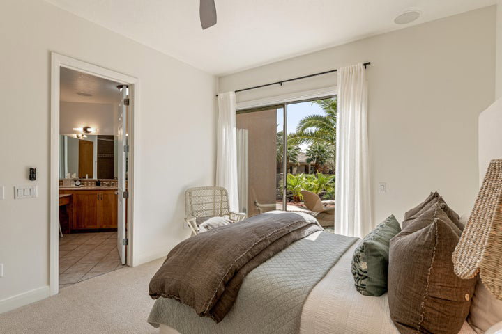 Bedroom with light carpet, access to outside, ceiling fan, and connected bathroom