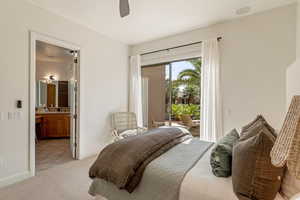 Bedroom with light carpet, access to outside, ceiling fan, and connected bathroom