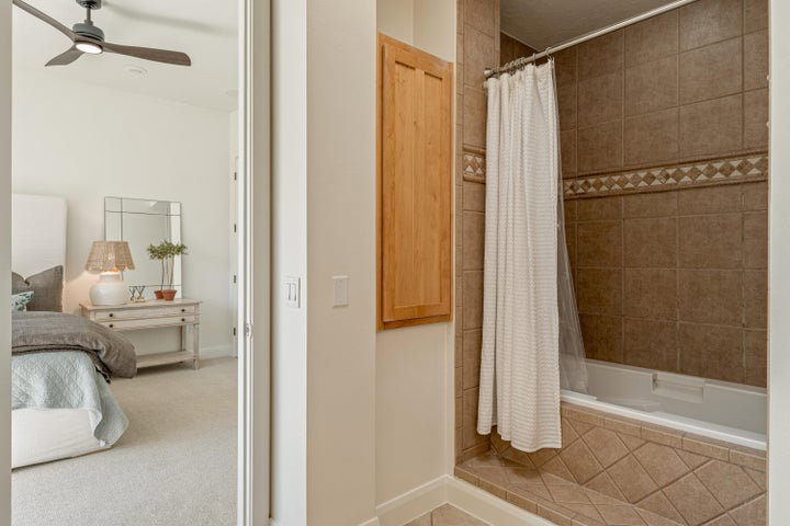 Ensuite bathroom featuring tiled shower / bath combo and ceiling fan