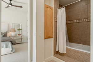 Ensuite bathroom featuring tiled shower / bath combo and ceiling fan