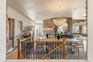 Dining space with a stone fireplace, hanging lights, and ceiling fan