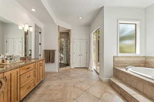 Bathroom with double vanity, a shower stall, a garden tub, light tile patterned flooring, and recessed lighting