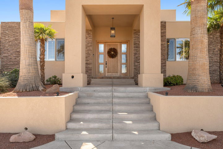 Doorway to property with stucco siding, stone siding, and a porch