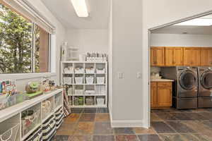 Laundry area with washing machine and dryer, stone tile floors, and cabinet space
