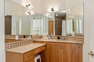 Full bathroom with vanity, a tile shower, and tasteful backsplash