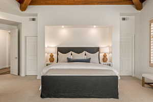 Bedroom with beamed ceiling and light colored carpet
