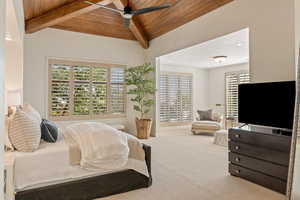 Bedroom featuring carpet floors, ceiling fan, multiple windows, wood ceiling, and vaulted ceiling with beams