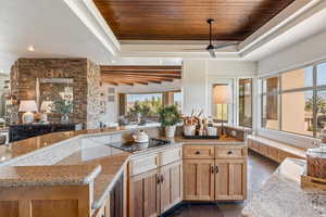 Kitchen featuring a wood ceiling with exposed beams, open floor plan, light stone countertops, and a ceiling fan