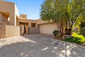 View of front facade with a gate, stucco siding, concrete driveway, and an attached garage