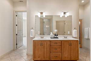 Full bath with double vanity and light tile patterned floors