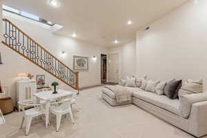 Living area with light colored carpet and recessed lighting