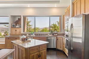 Kitchen with stainless steel appliances, light stone counters, a center island, recessed lighting, and a mountain view