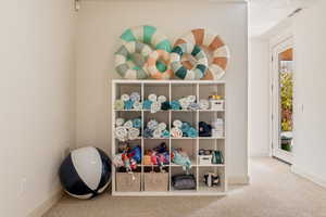 Recreation room with light colored carpet and baseboards