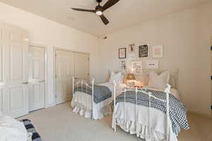 Bedroom with a closet, light colored carpet, and a ceiling fan