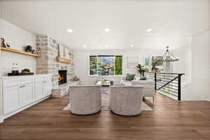 Living room with dark wood-style floors, hanging lights, and a stone fireplace