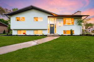 Split foyer home with brick siding, a chimney, and a front yard