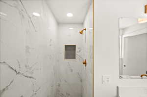Bathroom with a marble finish shower and vanity