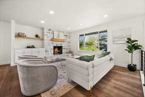 Living area with a fireplace, dark wood-type flooring, and recessed lighting