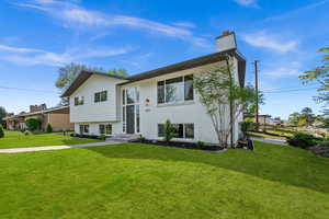 Bi-level home featuring brick siding, a front yard, and a chimney