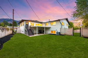 Back of property at dusk with a gate, a patio area, a fenced backyard, and brick siding