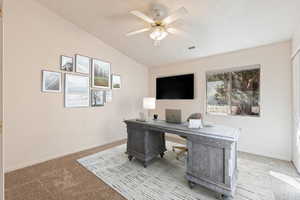 Office area with carpet floors, ceiling fan, and vaulted ceiling