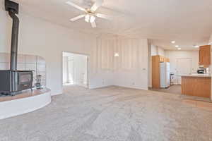 Unfurnished living room featuring a wood stove, light carpet, a ceiling fan, and recessed lighting