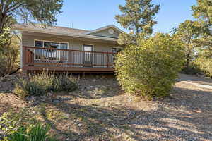 Rear view of property with a deck and a shingled roof