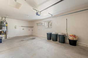 Garage featuring strapped water heater and a garage door opener