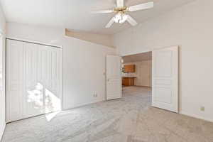 Unfurnished bedroom with light colored carpet, lofted ceiling, a closet, and ceiling fan