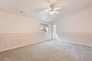 Spare room featuring vaulted ceiling, carpet floors, and ceiling fan