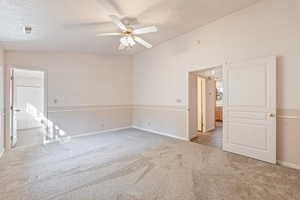 Unfurnished room featuring light colored carpet, ceiling fan, and vaulted ceiling