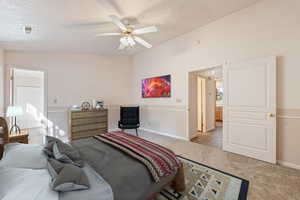 Carpeted bedroom with vaulted ceiling and a ceiling fan